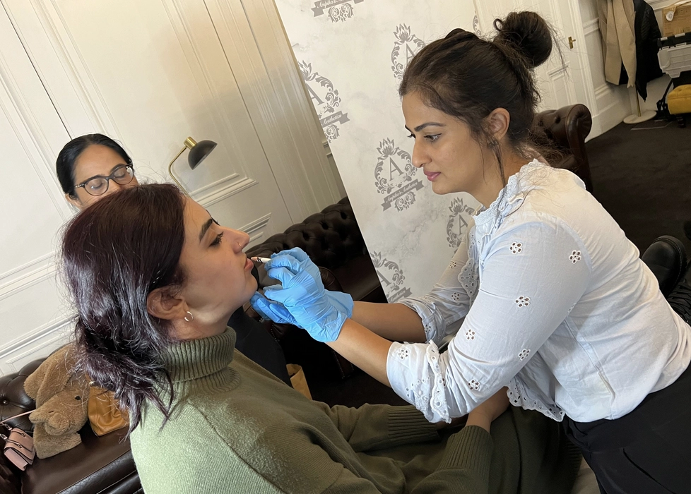 A beautician performing a filling on the lips of her client